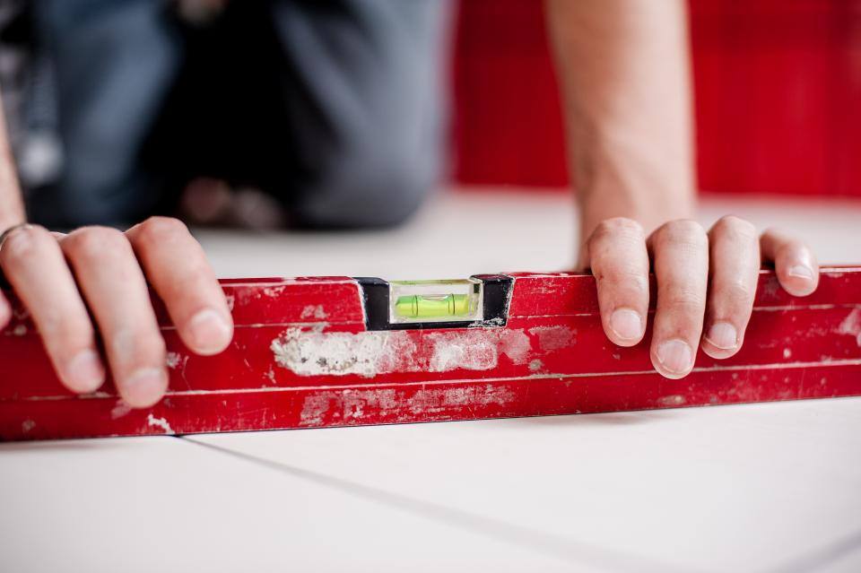 Hands checking a level on a wall